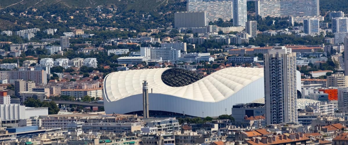A cityscape with a distinctive white stadium and modern high-rise buildings.
