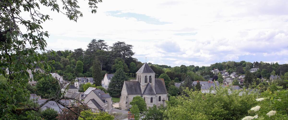 A village with a prominent church, surrounded by lush greenery and residential houses.