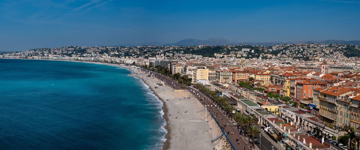 A coastal city with a long beach, dense urban buildings, and a mountainous backdrop.