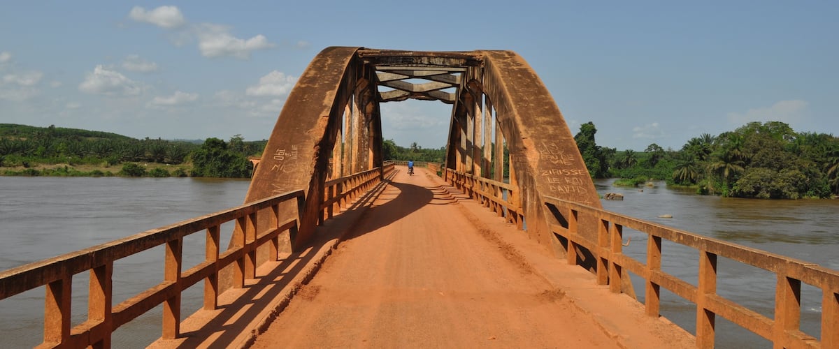 A rusted metal bridge over a river with a clear sky.