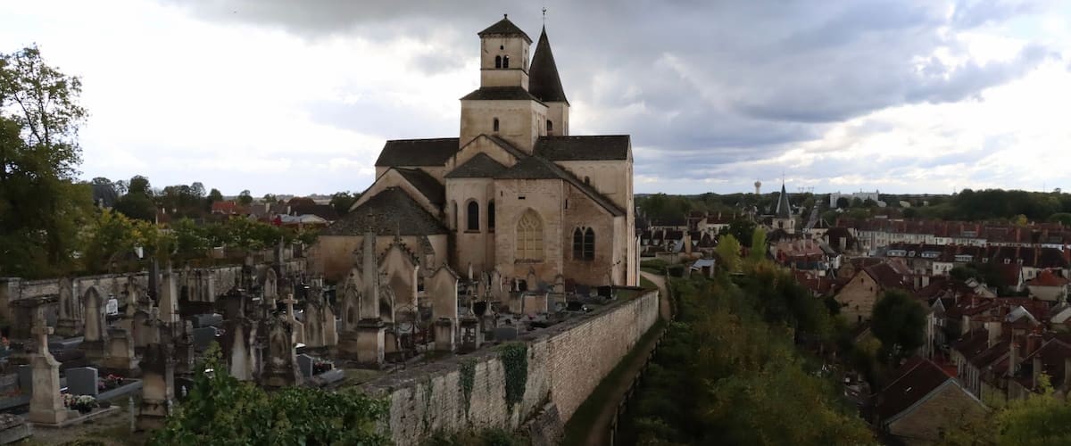 A historic church with a prominent tower, surrounded by a cemetery and a river.