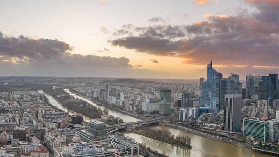 A cityscape with a river, modern buildings, and a bridge.