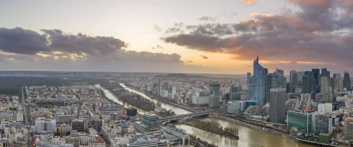 A cityscape with a river, modern buildings, and a bridge.