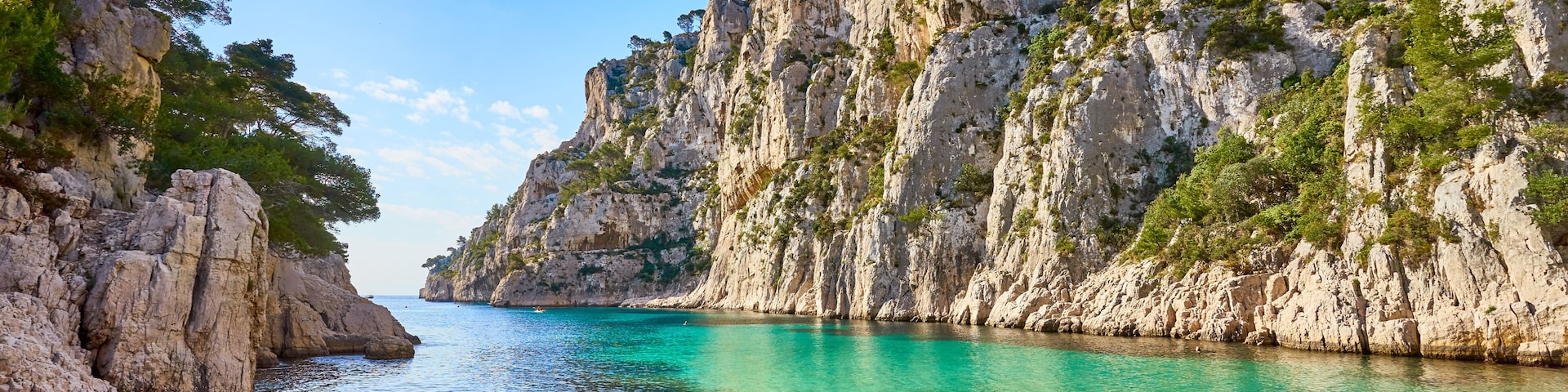 A coastal landscape with clear turquoise water, rocky cliffs, and sparse vegetation.