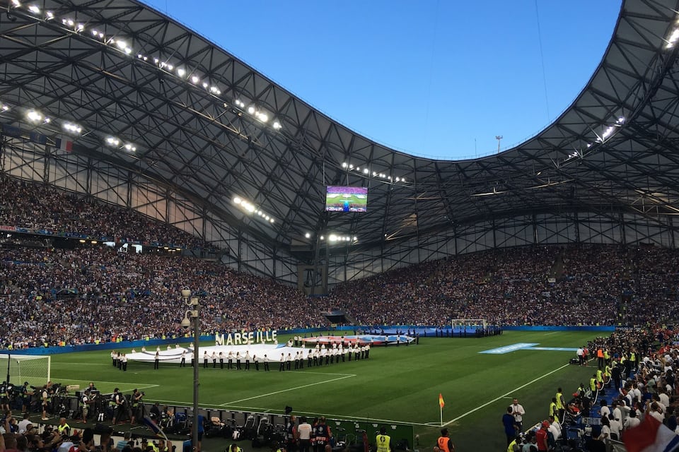 A large stadium with a curved roof and a crowd of spectators.