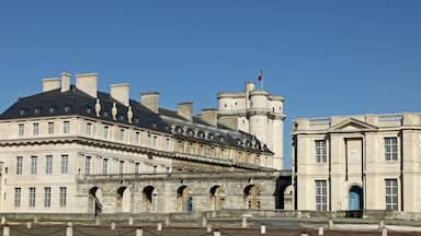Um edifício histórico com uma grande torre central, várias arcadas e uma bandeira no topo.