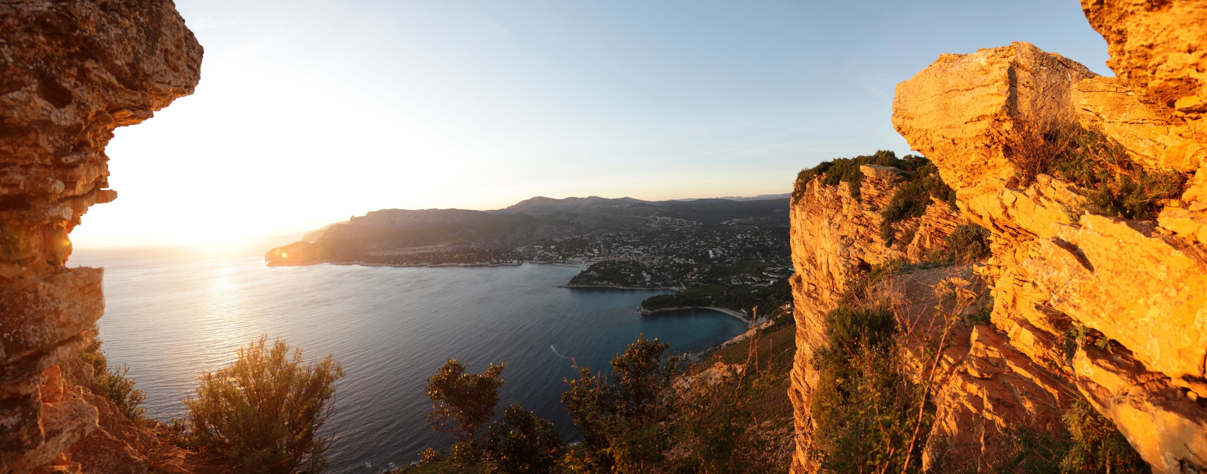 A coastal landscape with a prominent cliff and a view of the sea and a town below.
