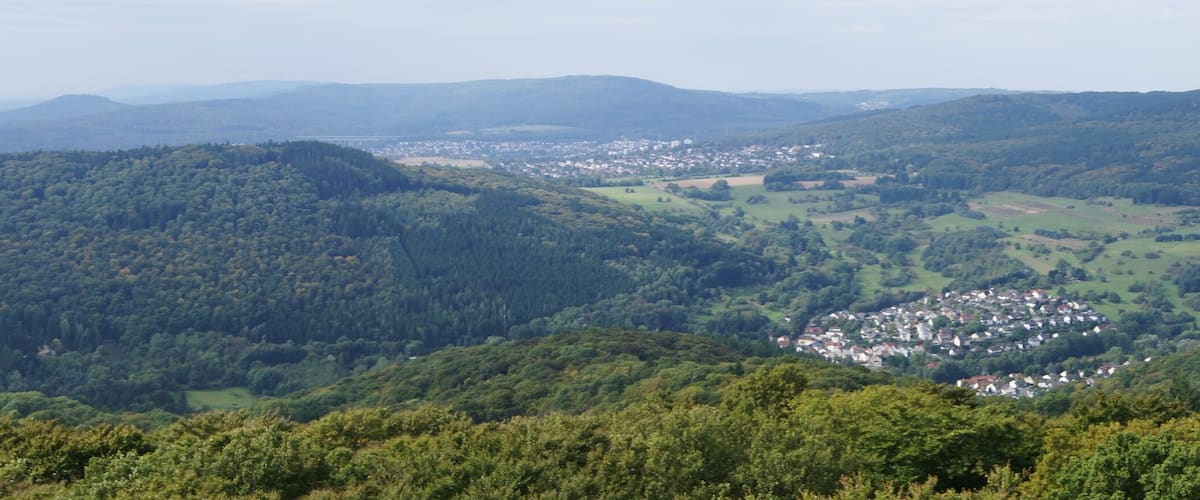 A mountainous landscape with dense forests and a small town nestled in the valley.
