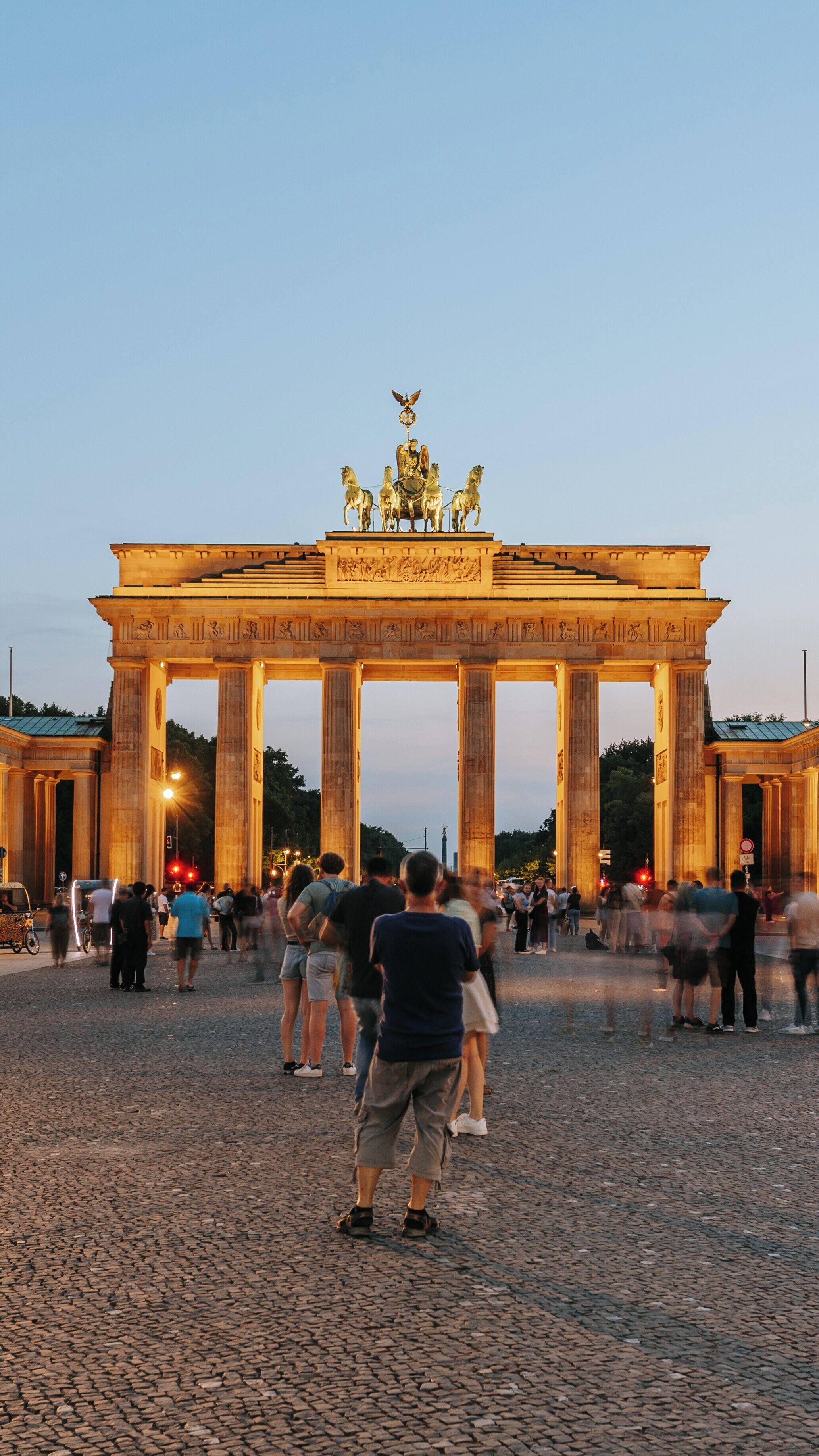 Visit to Brandenburg Gate at sunset with vibrant crowds enjoying the iconic landmark in Berlin, showcasing the historical architecture of the Brandenburg Region of Germany