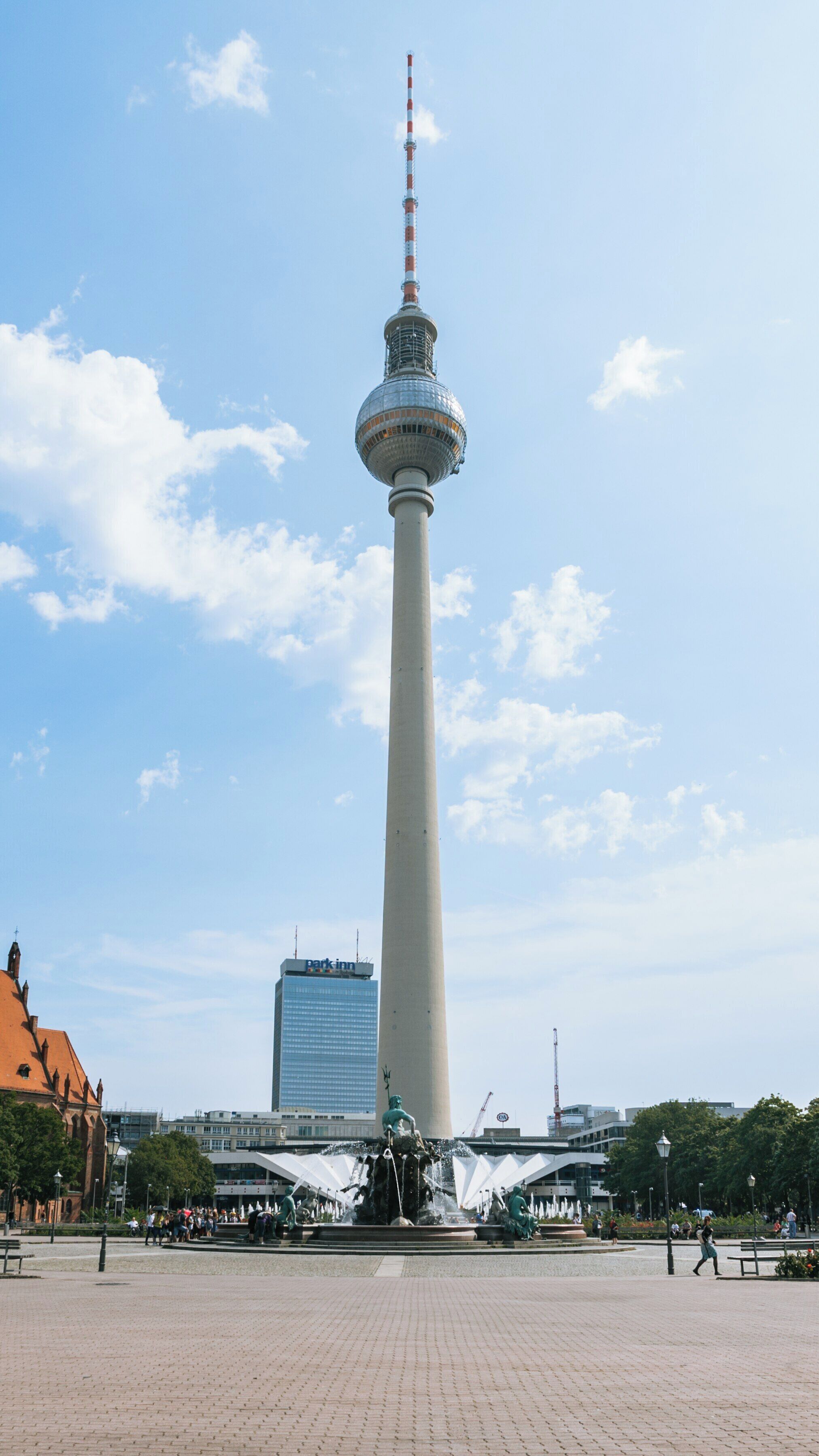Berlin TV Tower standing tall in Mitte on a sunny day while visitors enjoy the nearby fountain and cityscape views in Brandenburg Region
