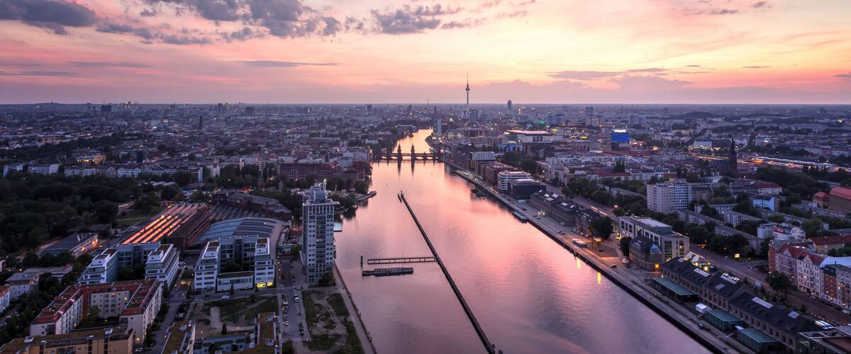 A cityscape with a river, bridges, and a sunset sky.
