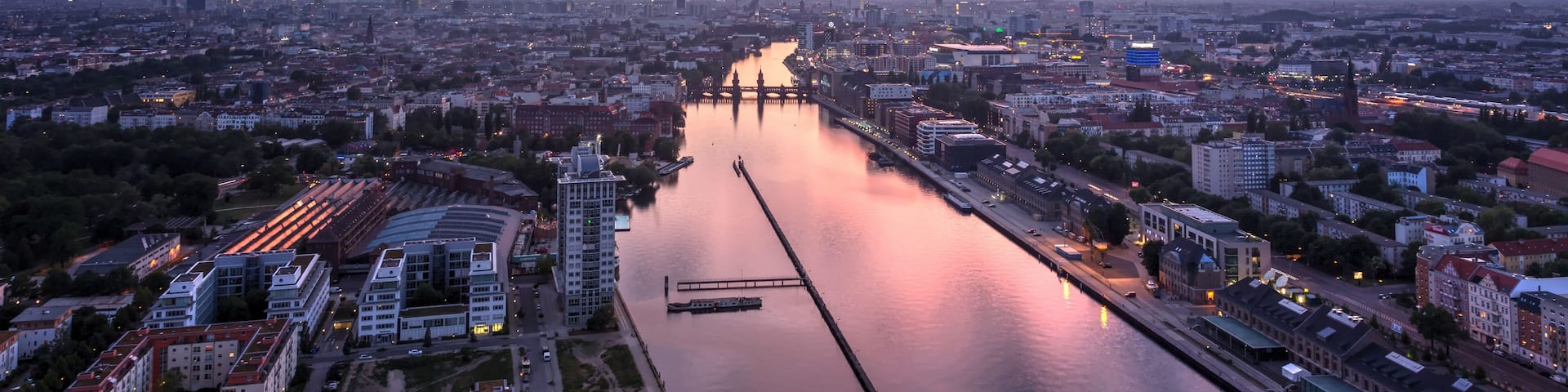 A cityscape with a river, bridges, and a sunset sky.