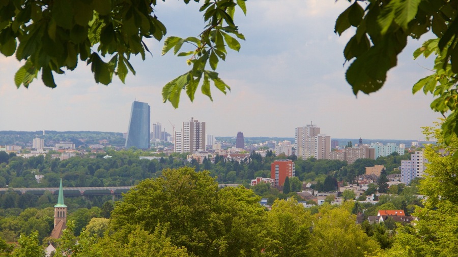 A cityscape with a prominent skyscraper, surrounded by greenery and smaller buildings.