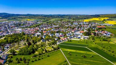 Une vue aérienne d’une ville entourée de champs verdoyants et de cultures aux couleurs jaunes.