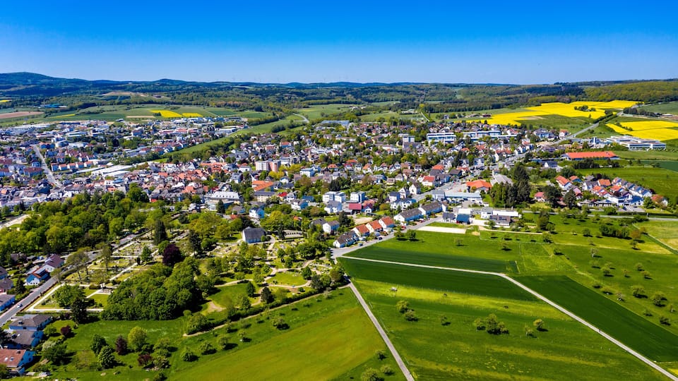 An aerial view of a town surrounded by green fields and yellow crops.