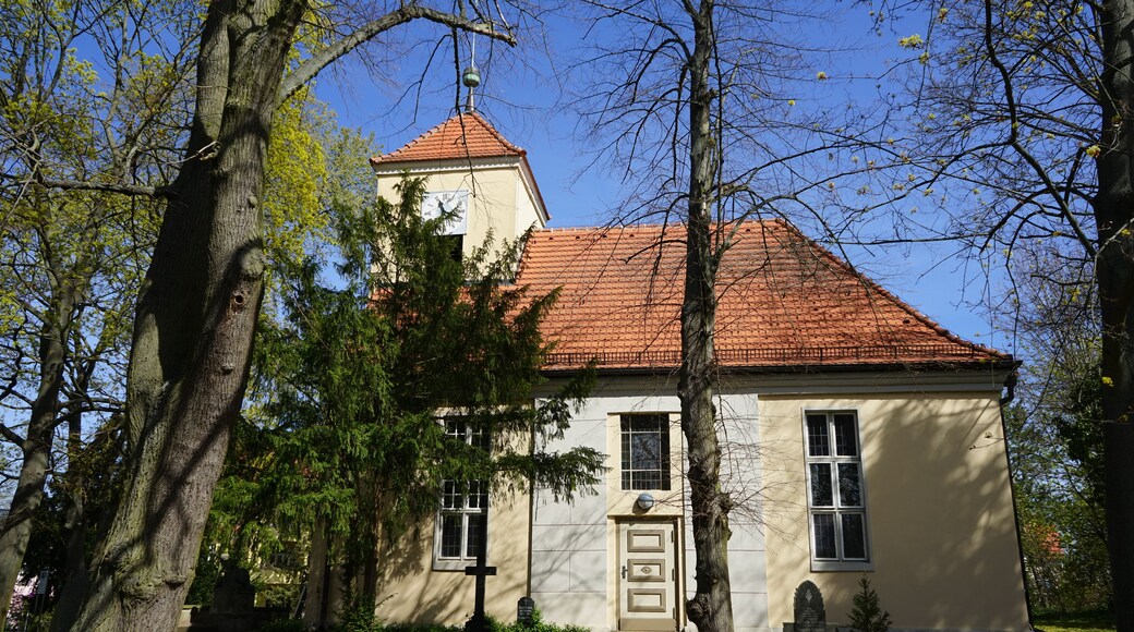 Eine Kirche mit rotem Ziegeldach, einer Uhr und einem Glockenturm.