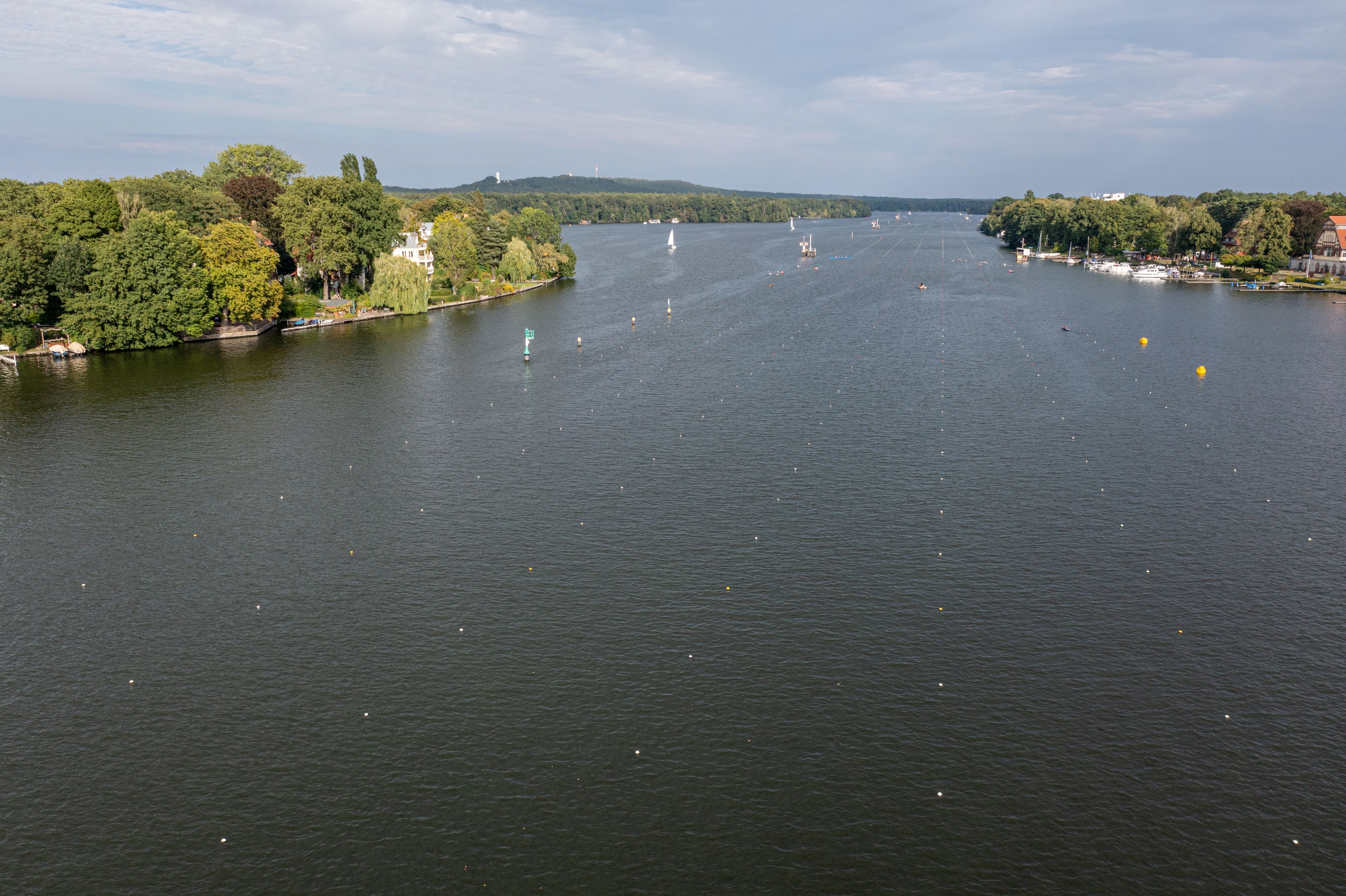 Ein Fluss mit Booten, einem Leuchtturm und einer bewaldeten Gegend.