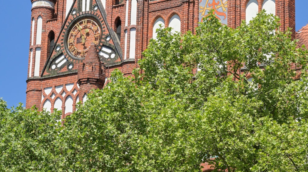 A historic church with a tall spire, intricate brickwork, and a large stained glass window.