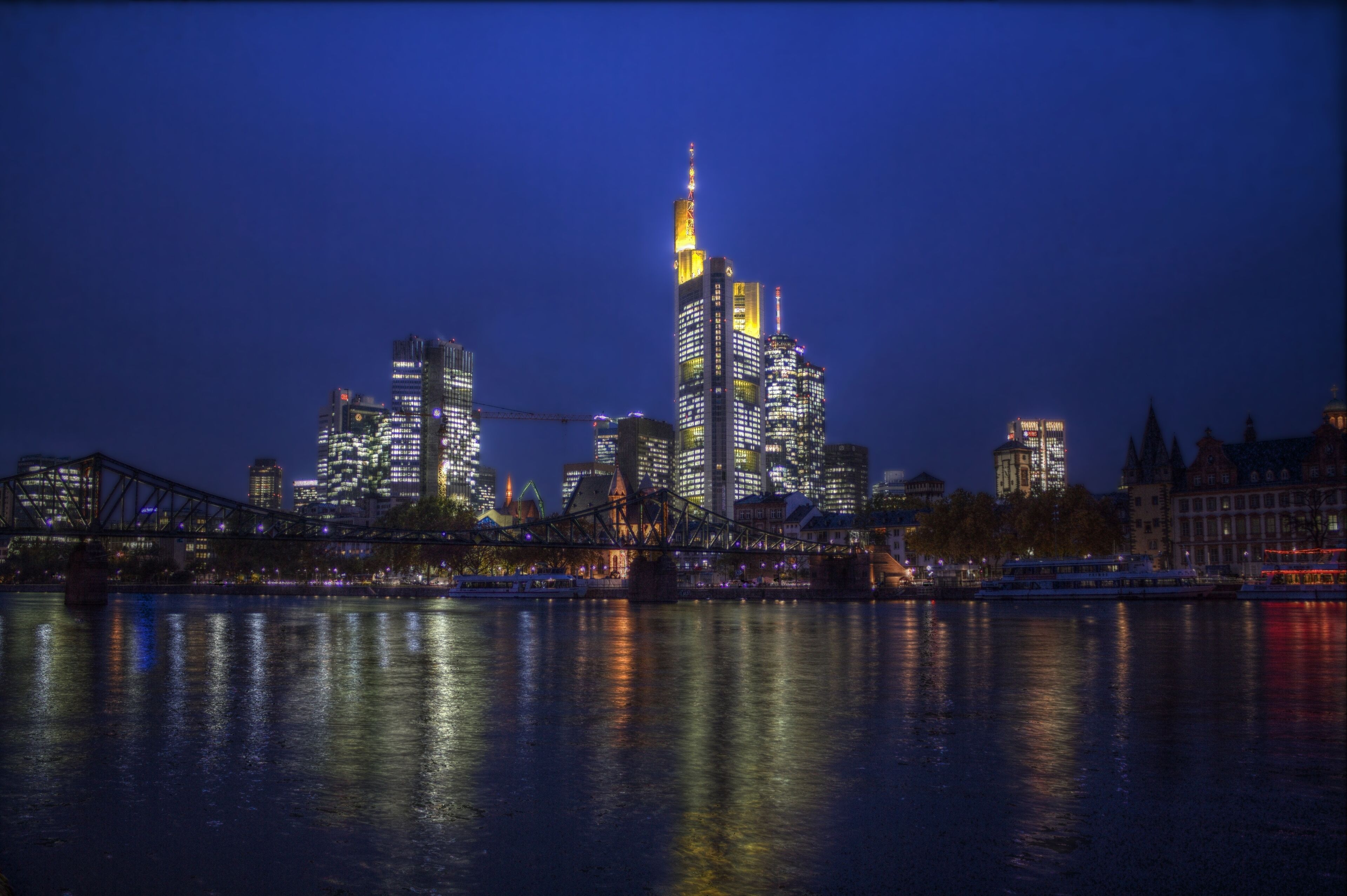 Een verlicht stadsbeeld bij nacht, met glinsterende wolkenkrabbers in het water.