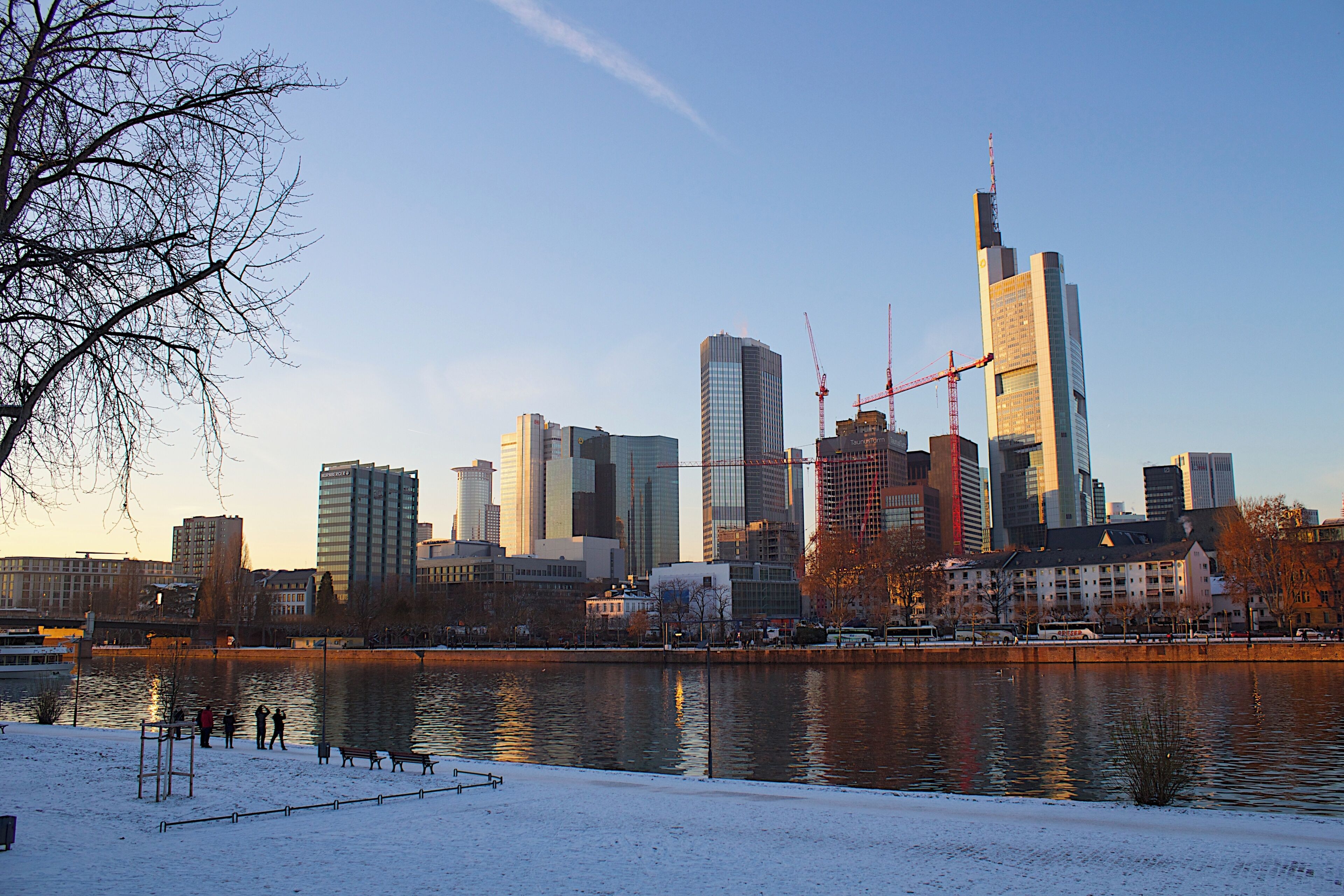 Une vue sur les toits d’une ville, avec des gratte-ciel modernes, une rivière et un parc enneigé.
