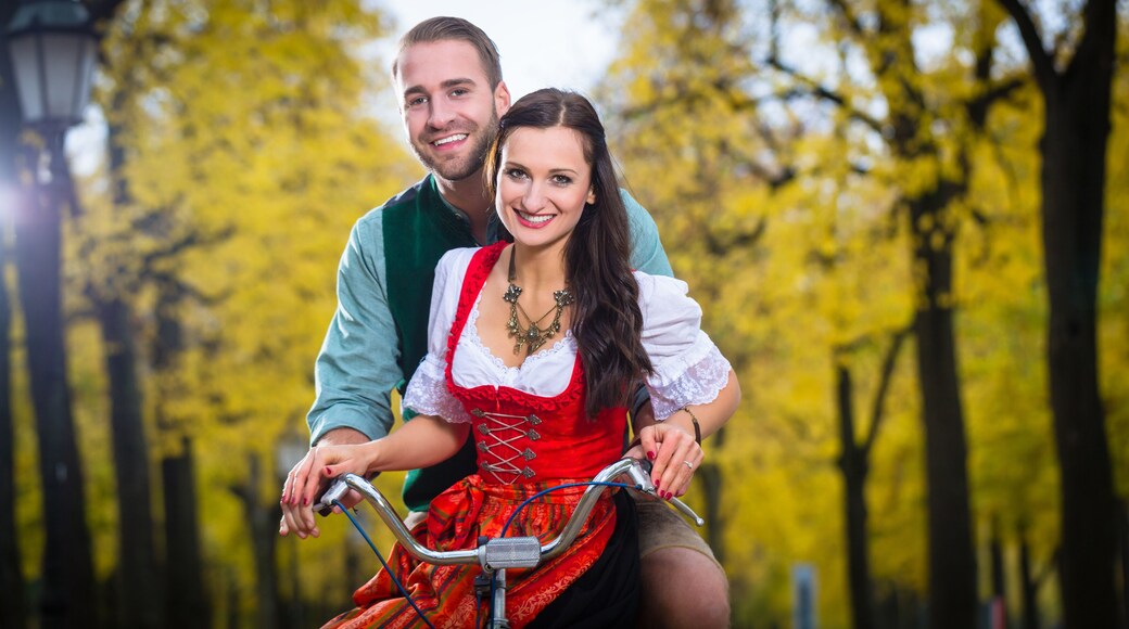 Mann und Frau in süddeutscher Tracht fahren auf Fahrrad und lachen