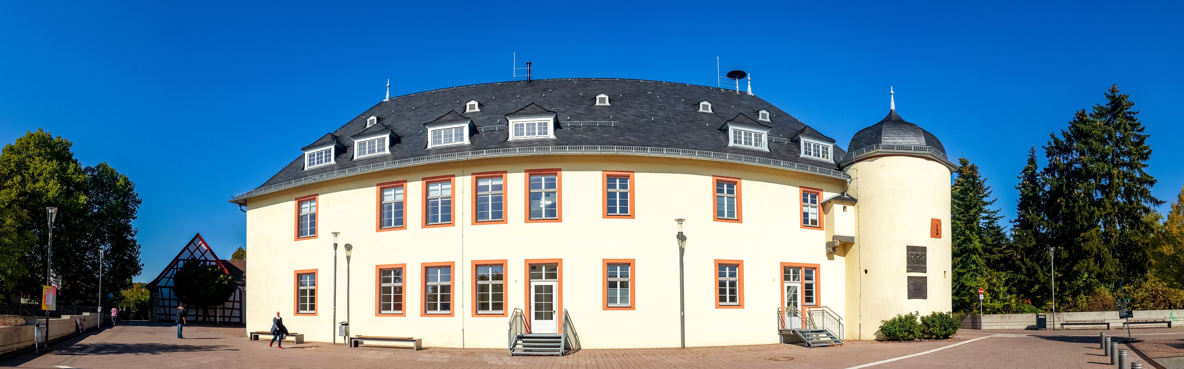 A large, yellow building with a black roof and a round tower.