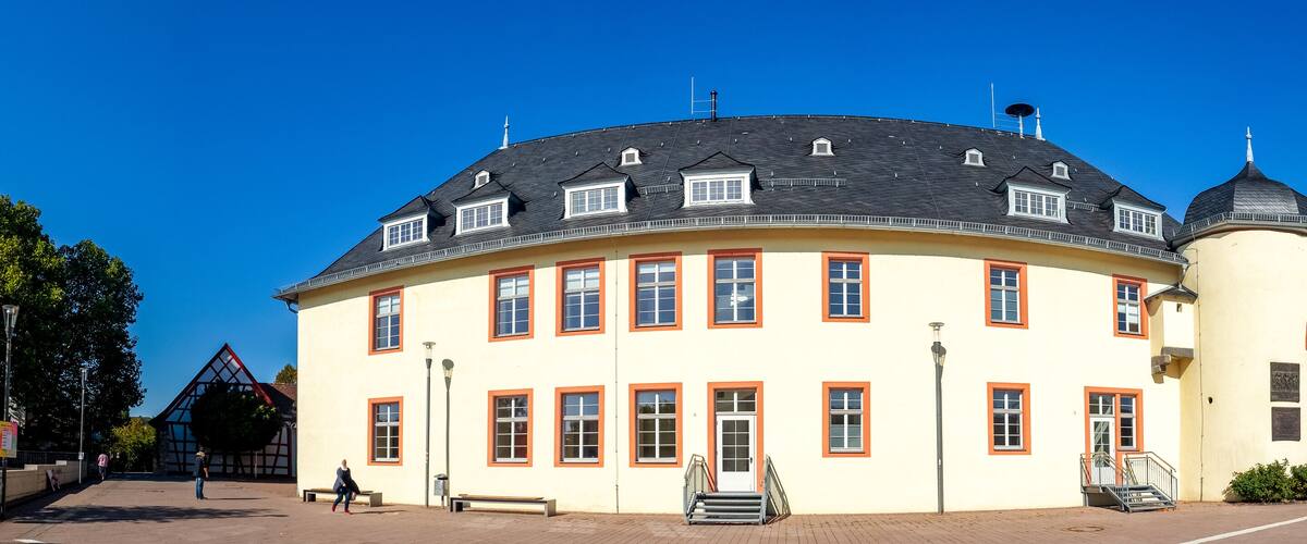 A large, yellow building with a black roof and a round tower.