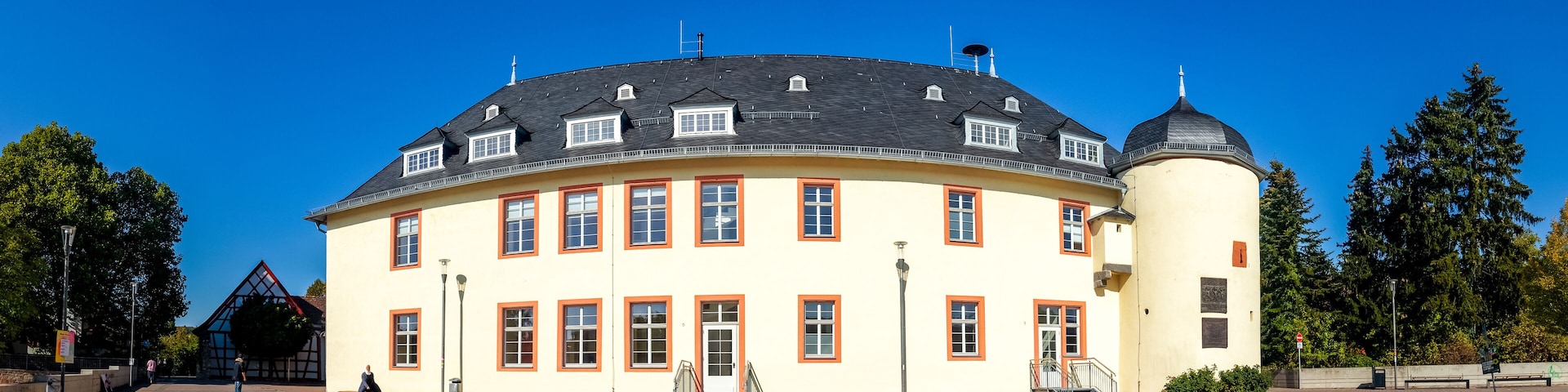 A large, yellow building with a black roof and a round tower.
