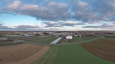 Vista aérea de uma cidade com campos, estradas e um céu nublado.