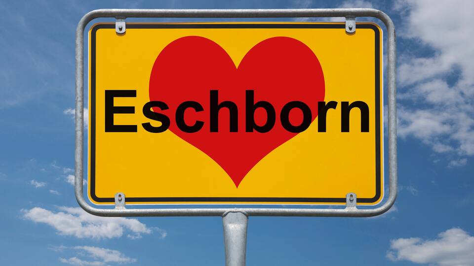 A sign with a heart and the word "Eschborn" against a blue sky with clouds.