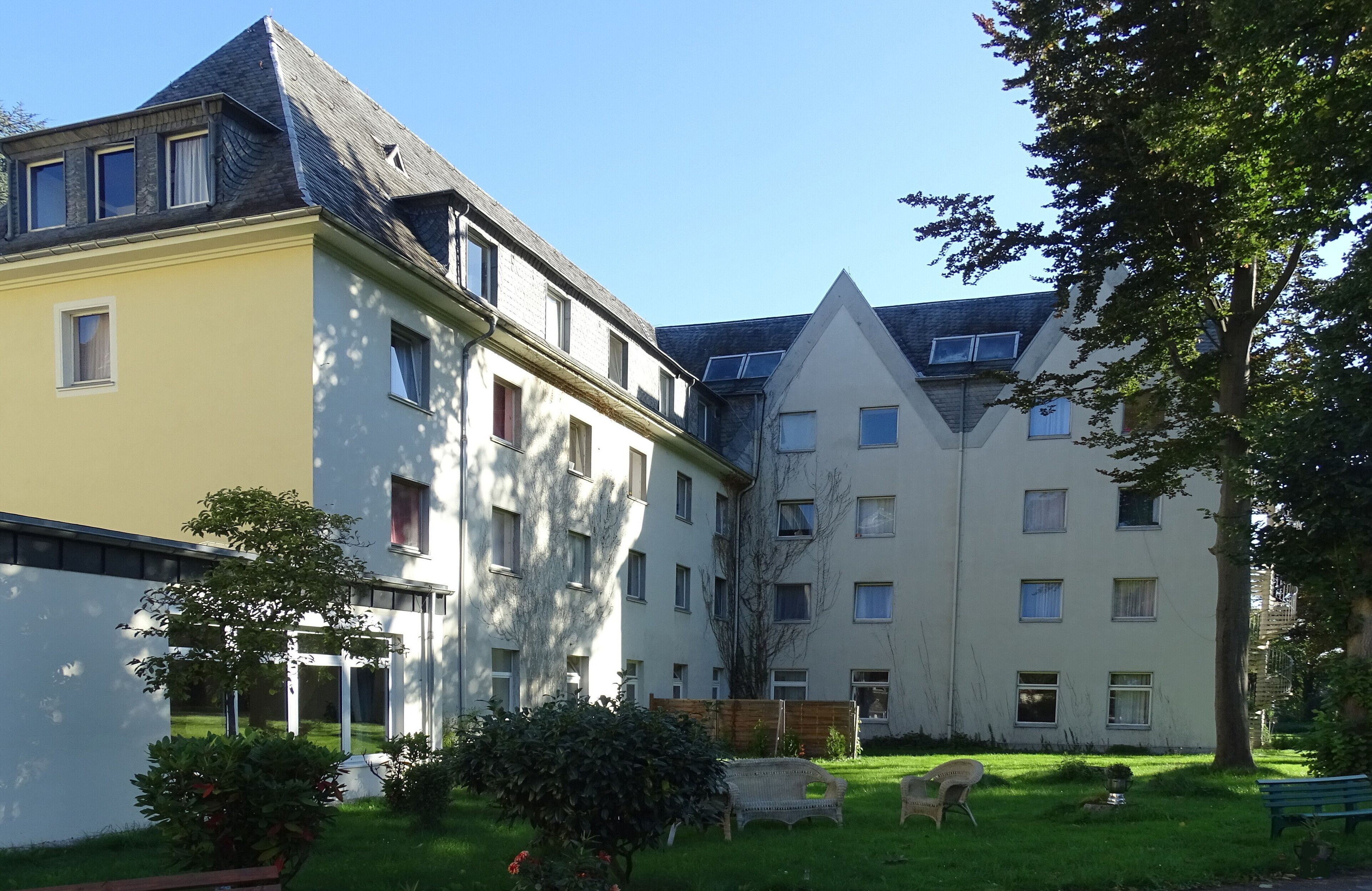 A residential complex with multiple buildings, a grassy courtyard, and a few trees.