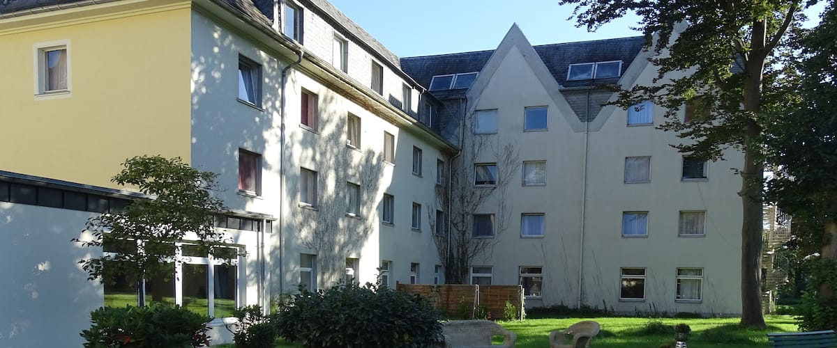 A residential complex with multiple buildings, a grassy courtyard, and a few trees.