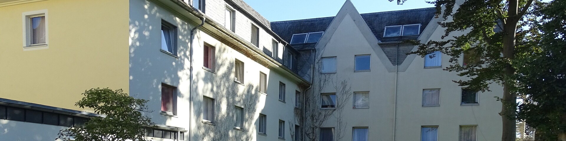 A residential complex with multiple buildings, a grassy courtyard, and a few trees.