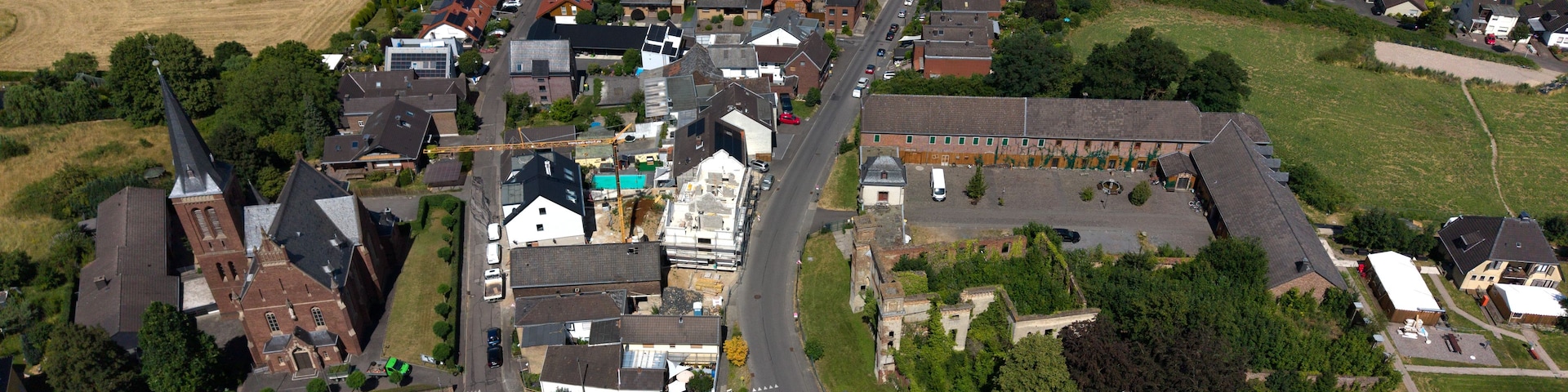 An aerial view of a small town with a mix of residential houses, a church, and a large industrial building.