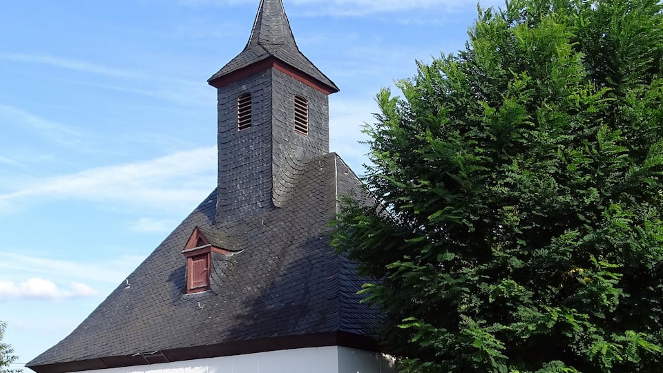 A white church with a black roof and a small bell tower.