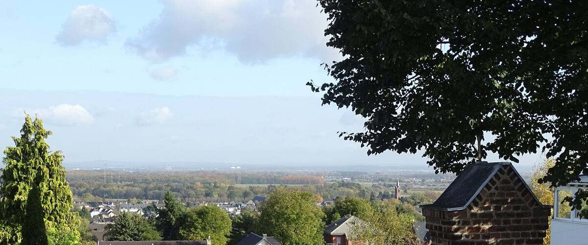 A rural landscape with a grassy field, a brick structure, and houses in the background.