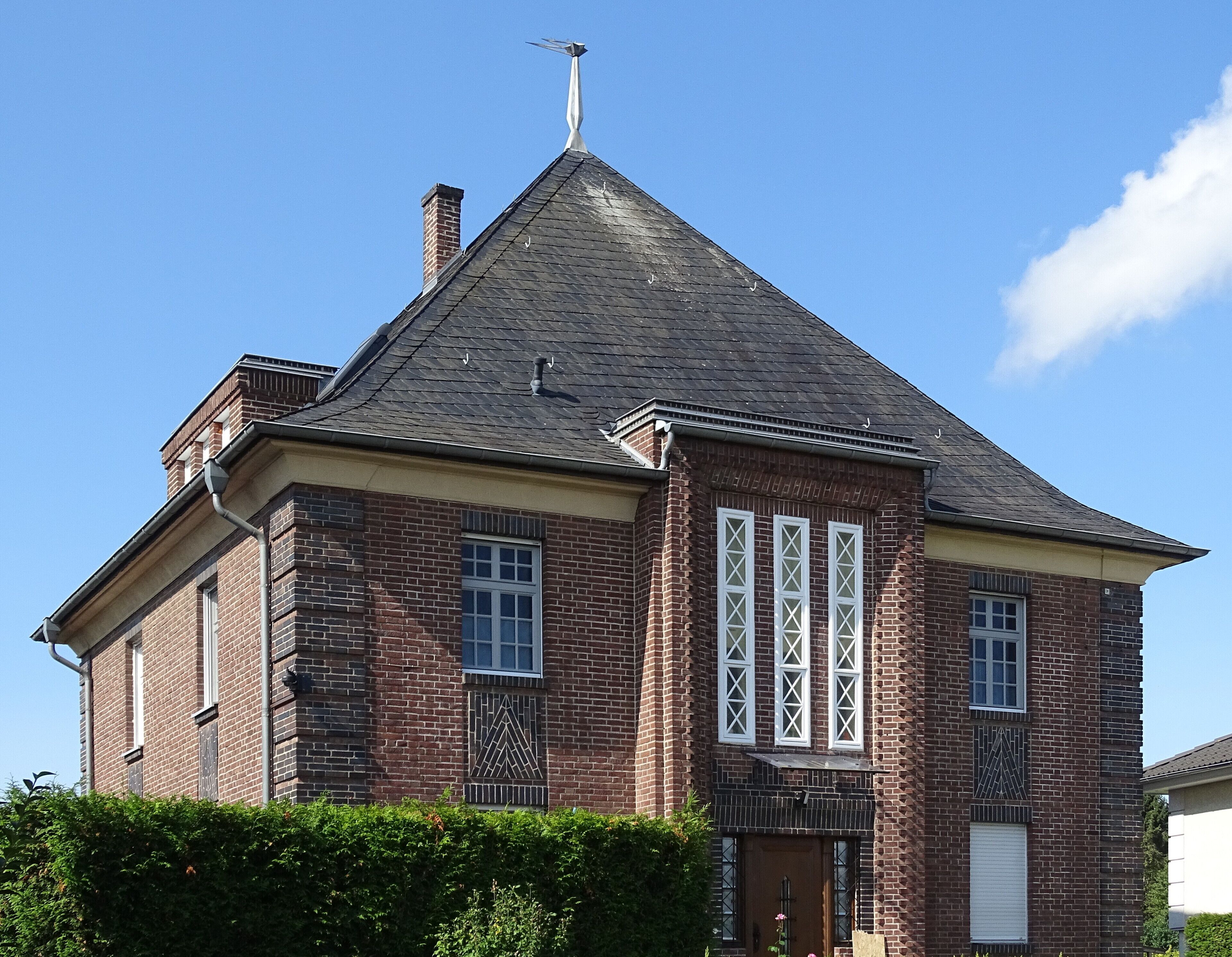 A brick house with a steep gabled roof and a chimney.
