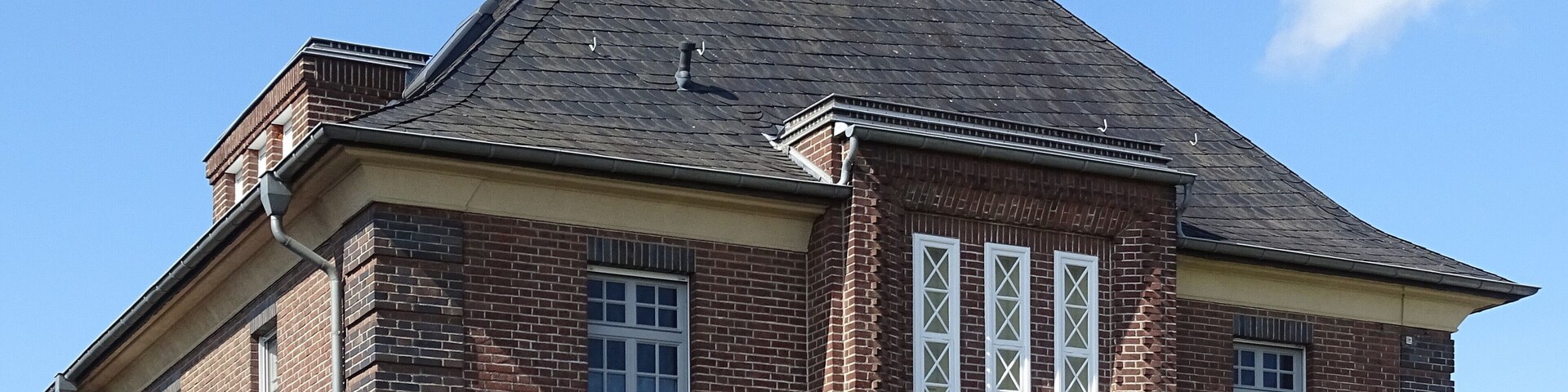A brick house with a steep gabled roof and a chimney.