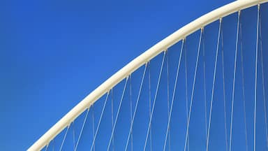 Uma ponte suspensa branca contra um céu azul límpido.