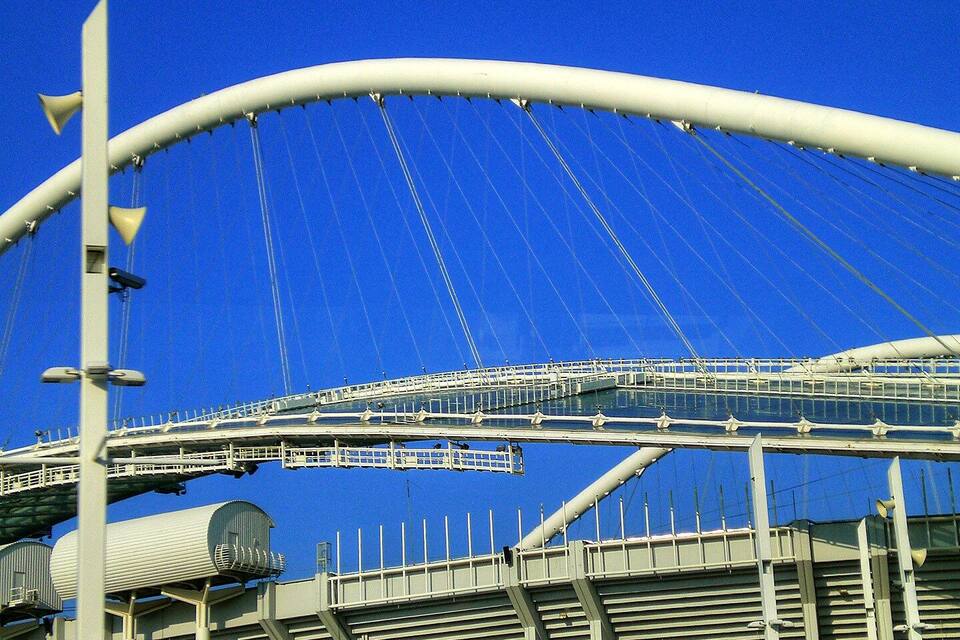 Uma grande ponte estaiada branca, com vários cabos e uma passarela.