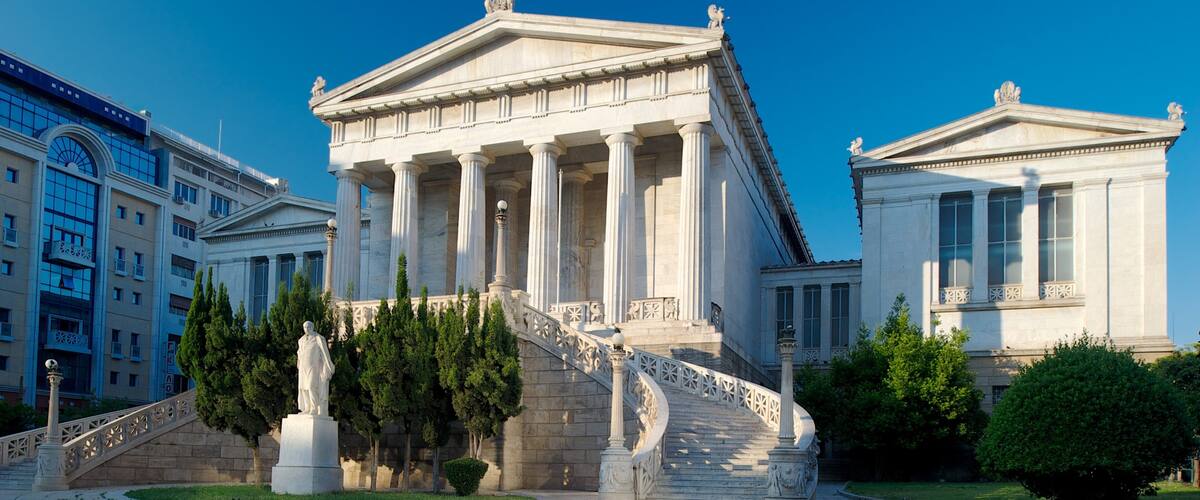 A neoclassical building with columns and a statue in front.