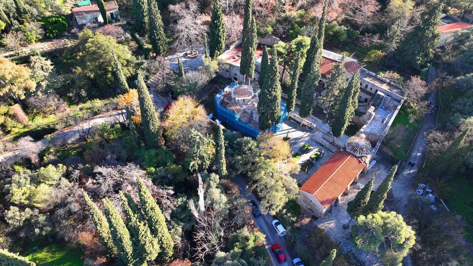 An aerial view of a historic site with a central dome, surrounded by trees and stone buildings.