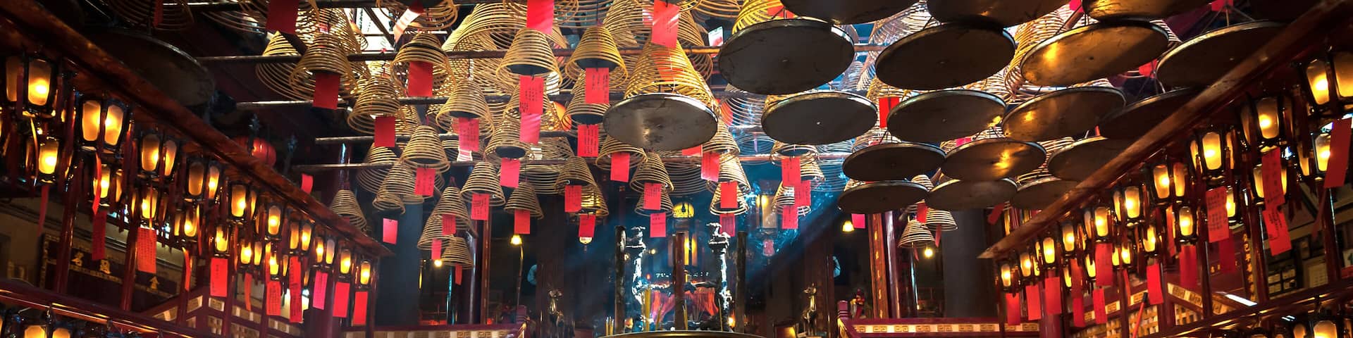 A temple interior with golden statues, red lanterns, and a central incense burner.