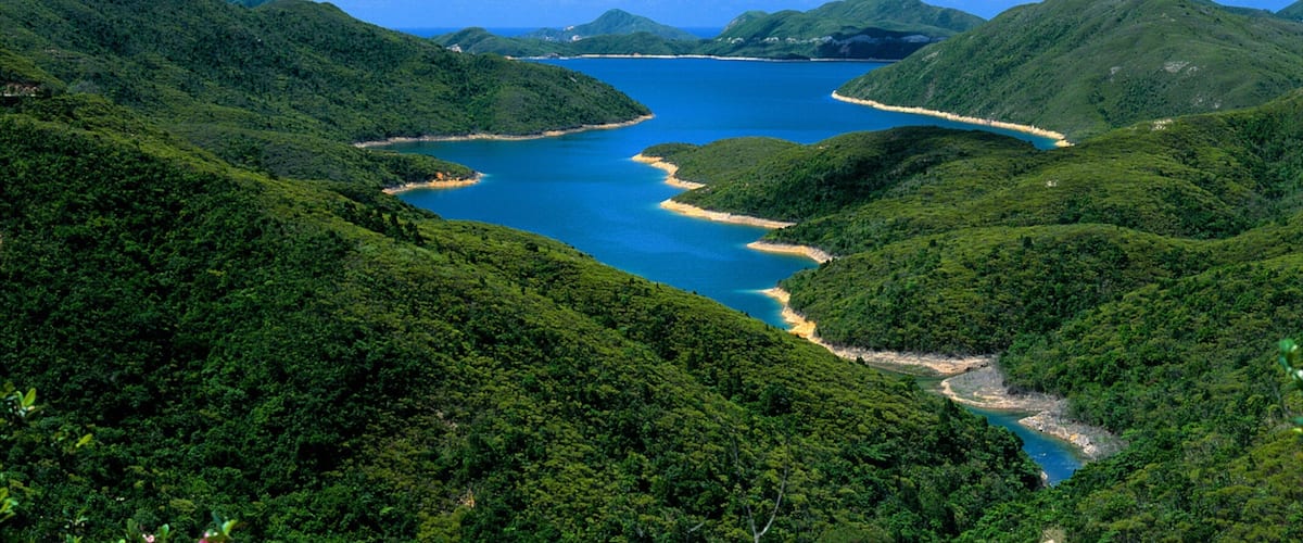 A coastal landscape with lush green hills and a clear blue sea.
