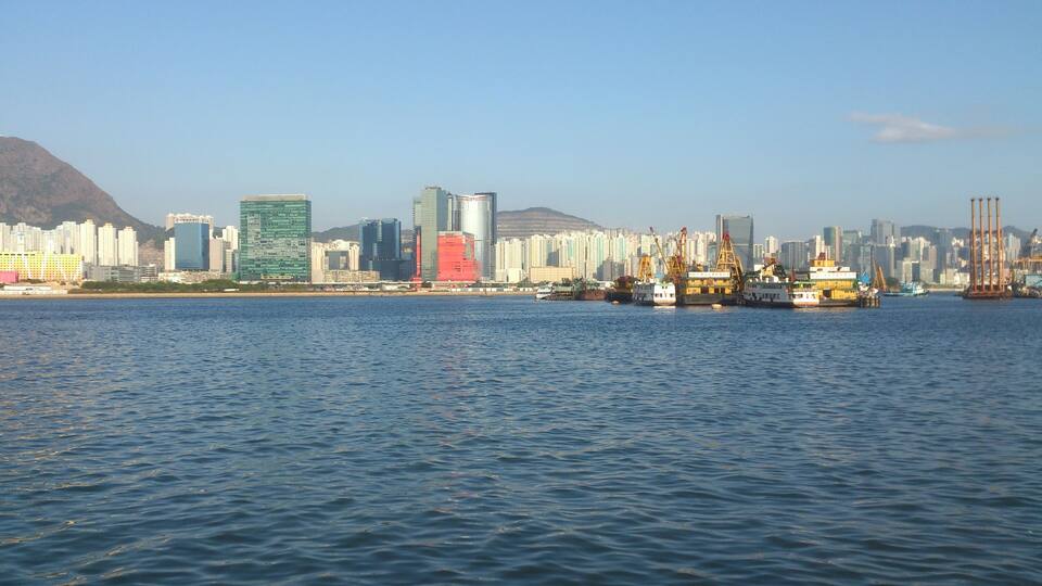 A coastal cityscape with modern skyscrapers and a harbor with ships.