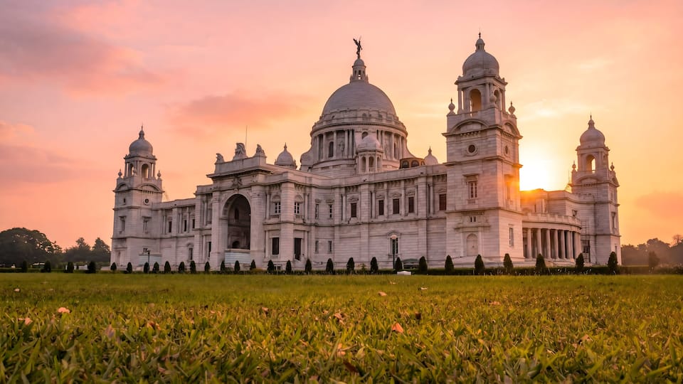 A large, ornate building with domes and towers, surrounded by a well-maintained lawn.