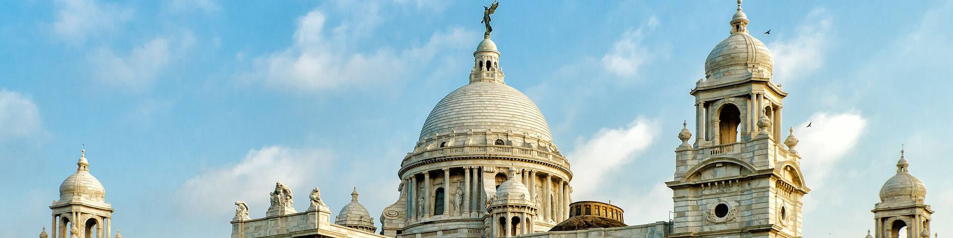 A grand, historic building with multiple domes and towers, surrounded by well-maintained lawns and trees.