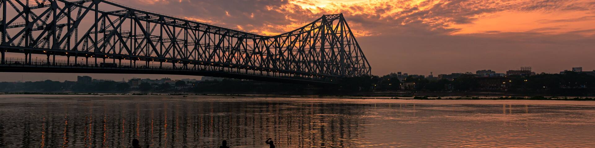 A bridge over water during sunset with a pink sky.
