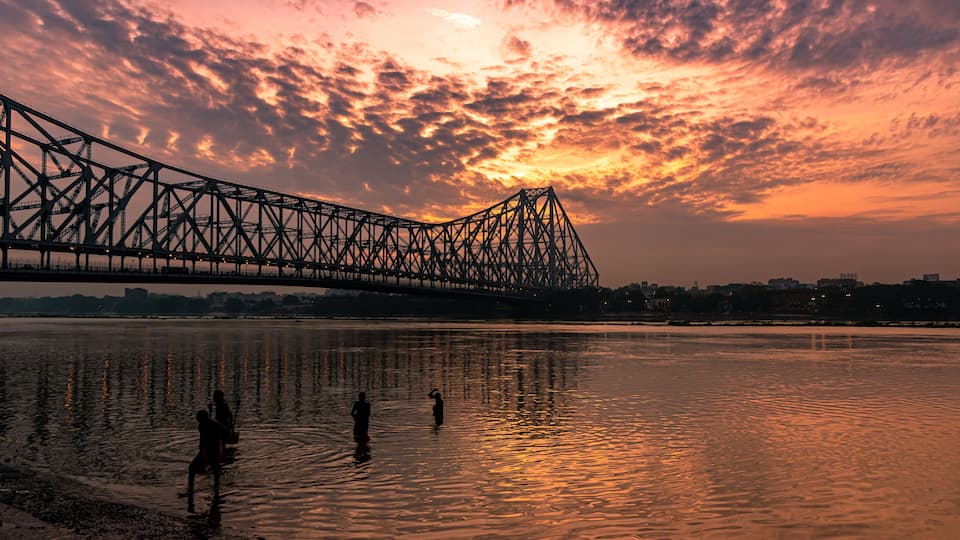 A bridge over water during sunset with a pink sky.