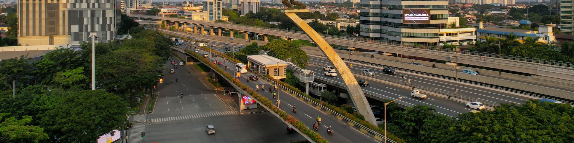 A cityscape with modern high-rise buildings, a busy highway, and a large sculpture.